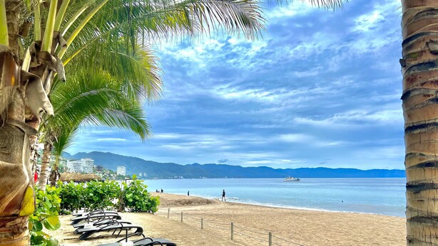 A beach with lounge chairs and a view of the sea and mountains. - Pavilion Paradise - Steps away from everything! (Puerto Vallarta)