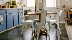 A kitchen with blue cabinets, a dining table with chairs, and a fire extinguisher on the wall.
