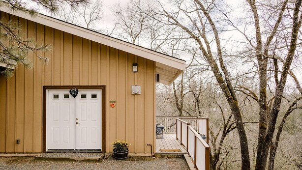 A wooden building with a white door, a small porch, and a gravel driveway.