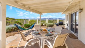 A covered patio with a table set for dining, a hammock, and a view of the desert landscape. - Incredible VIEWS, pool, spa, ping pong table, by GOLF course, bike and walk path (Tucson)