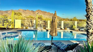 A pool with lounge chairs and an umbrella, surrounded by desert plants and mountains in the background. - Incredible VIEWS, pool, spa, ping pong table, by GOLF course, bike and walk path (Tucson)