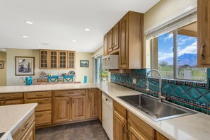 Enjoy a kitchen with a large window offering a view of the surrounding landscape, featuring a stainless steel sink, microwave, and dishwasher.