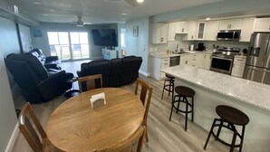 Una sala de estar moderna con comedor, una cocina equipada con electrodomésticos de acero inoxidable y un ventilador de techo.