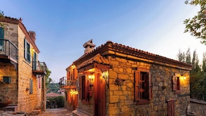 A stone building with a tiled roof, wooden shutters, and a stone staircase leading to the entrance. - Orion Adatepe (Ayvacik)