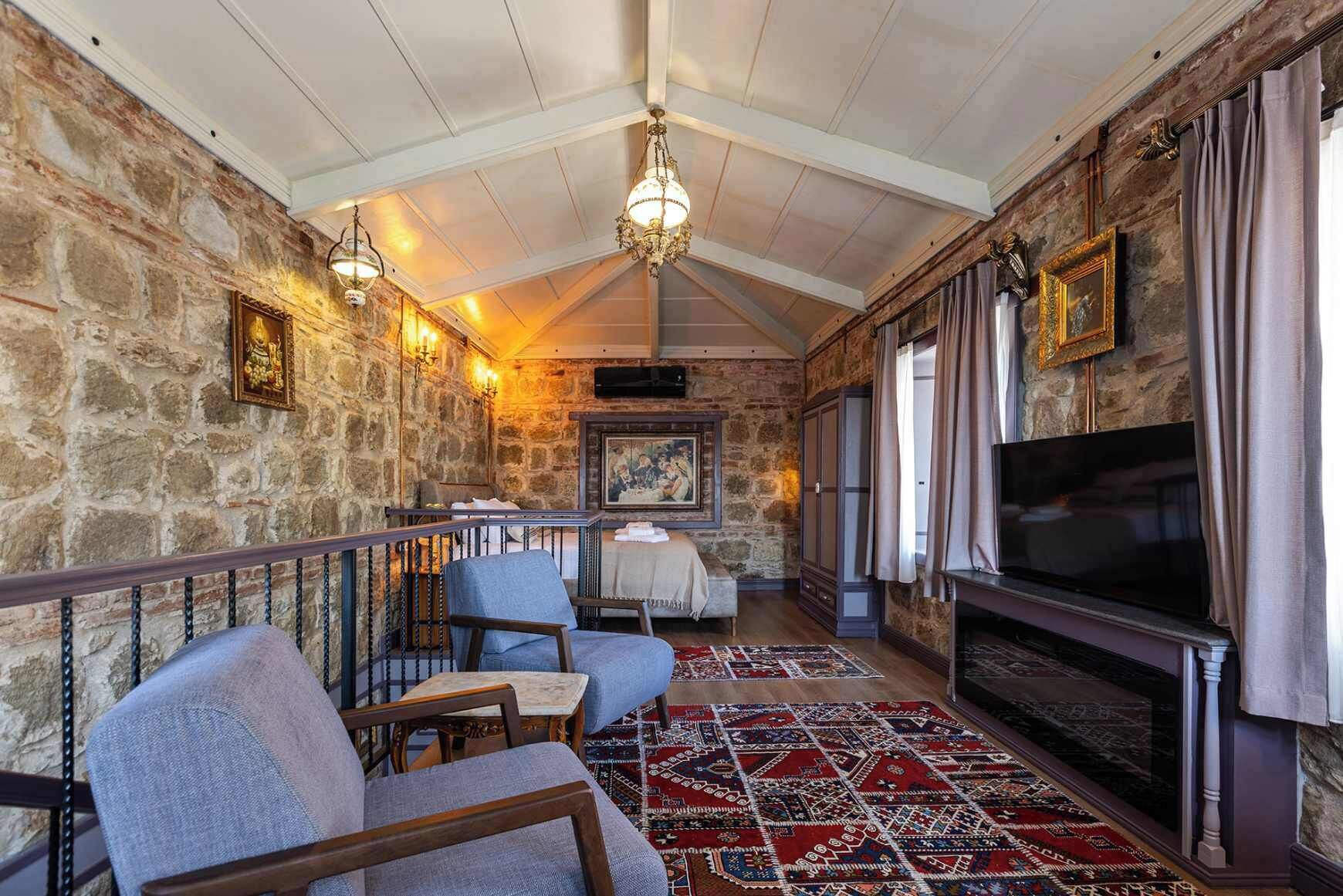 A cozy room with stone walls, a fireplace, a TV, and comfortable seating.