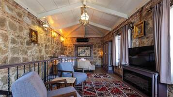 A cozy room with stone walls, a fireplace, a TV, and comfortable seating.