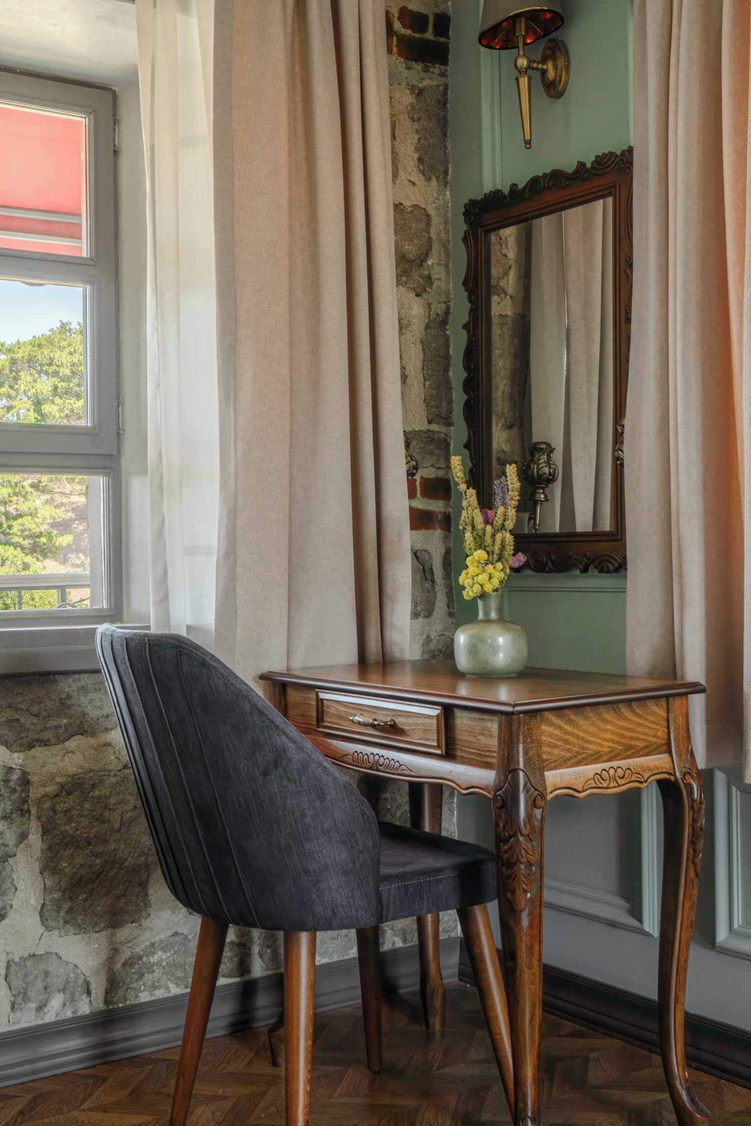 A room with a desk, chair, and a vase of flowers.