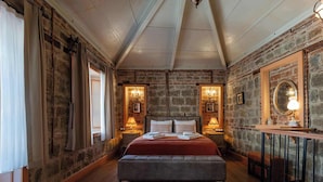 A bedroom with a large bed, stone walls, and a sloped ceiling. - Orion Adatepe (Ayvacik)
