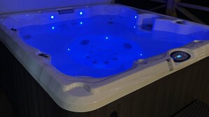 Un jacuzzi con luces LED azules, un panel de control y revestimiento de madera.
