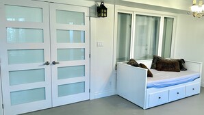 Un dormitorio con cama, armario y ventana con cortinas.