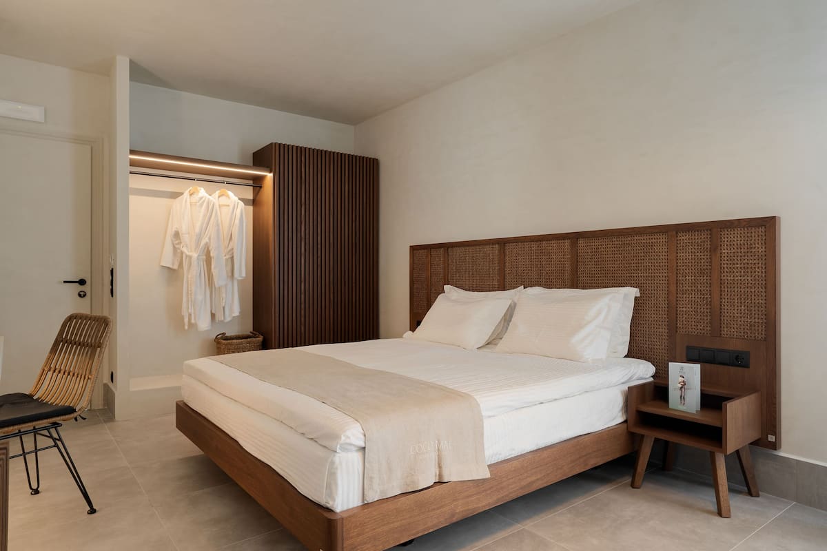 Een slaapkamer met een houten bed, een nachtkastje met een boek en een rieten stoel.