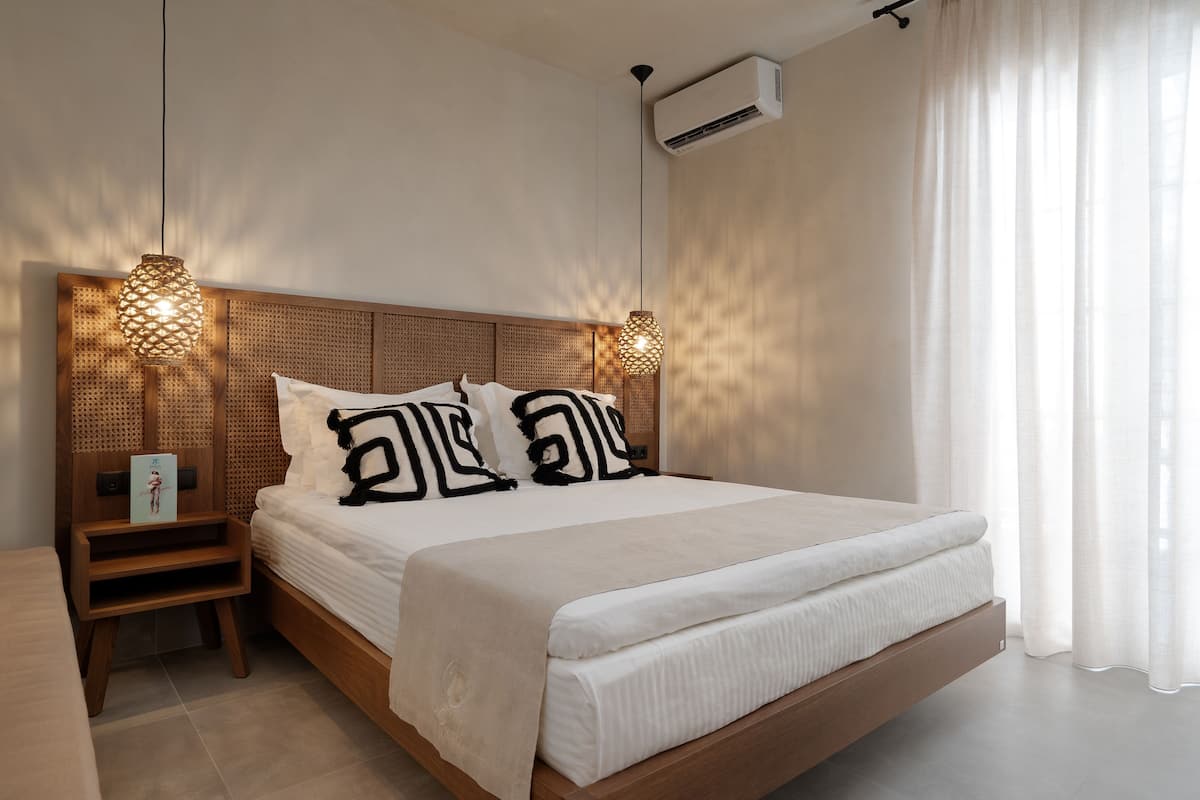 Een moderne slaapkamer met een houten hoofdbord, een groot bed met witte beddengoed, twee nachtkastjes en een staande lamp.