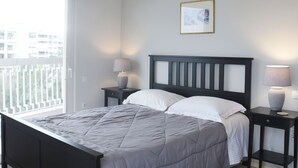 Een moderne slaapkamer met een bed, nachtkastjes, een hanglamp, een raam en een airconditioning.