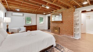A bedroom with a large bed, a fireplace, a wooden ceiling, and a brick wall. - Peaceful Mountain Retreat Near Appalachian Trail, Wineries, Breweries and More (Bluemont)