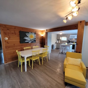 Un comedor con pared de madera, una mesa con sillas amarillas y un sofá amarillo.
