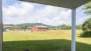 A covered outdoor area with a view of a brick building and a grassy field.
