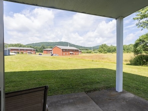 A covered outdoor area with a view of a brick building and a grassy field.