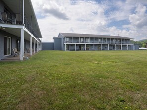 Un edificio con techo plano, varios balcones y un patio cubierto de césped.
