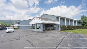 A Colonial Brick Inn & Suites with a covered entrance, parking lot, and a building with a flat roof.