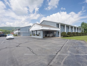 A Colonial Brick Inn & Suites with a covered entrance, parking lot, and a building with a flat roof.
