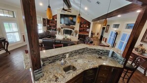 A modern kitchen with a granite countertop, a built-in sink, and wooden cabinets. - Newly Renovated Private Ranch Get-A-Way (Pilot Point)