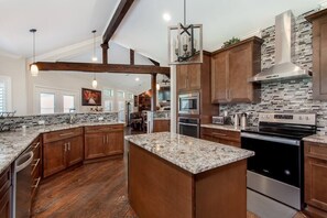 A spacious kitchen with wooden cabinets, granite countertops, and stainless steel appliances. - Newly Renovated Private Ranch Get-A-Way (Pilot Point)
