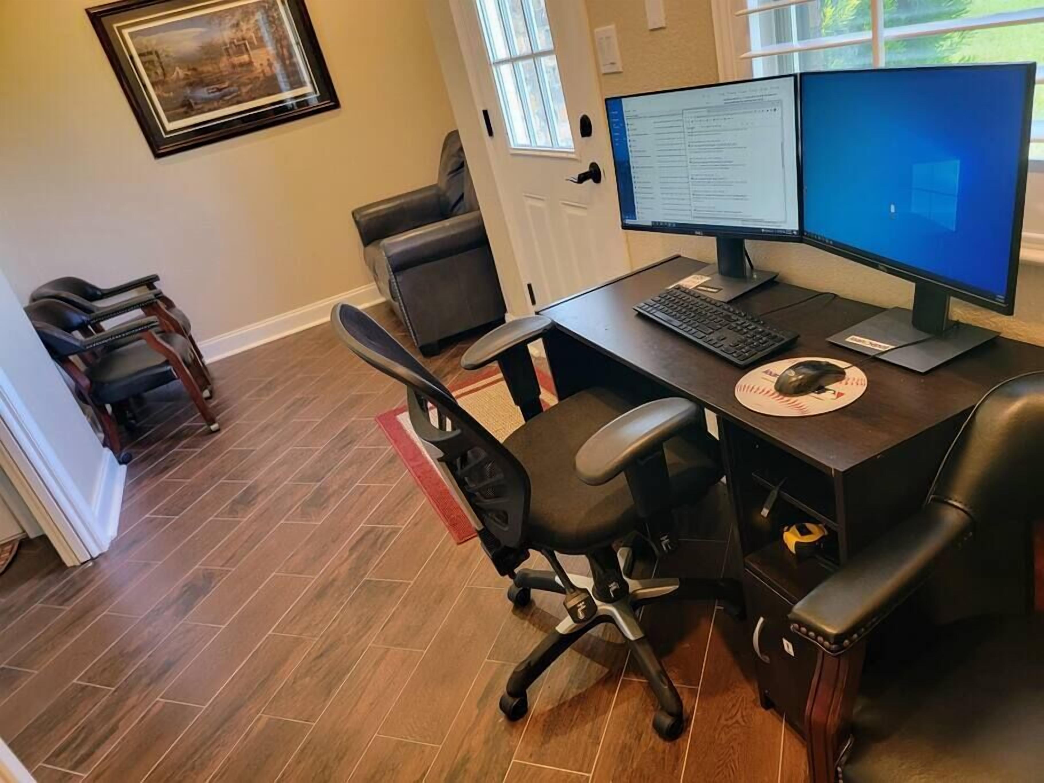 A home office with a desk, two monitors, a keyboard, a mouse, and a chair.
