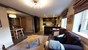 A modern living room with a sofa, a coffee table, and a dining area with chairs and a table. - Former showhome with indoor pool & gym (Oakhill)