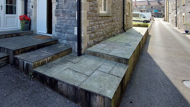 A stone building with a white door and steps leading to a porch. - Former showhome with indoor pool & gym (Oakhill)