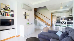 Una sala moderna con un sofá gris, un televisor de pantalla plana y una estantería.