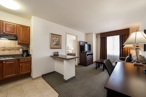 Una habitación de hotel compacta con kitchenette, comedor y zona de estar.