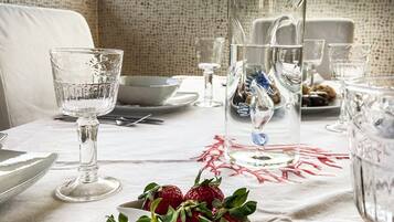 Une table à manger dressée avec de beaux verres, un saladier rempli de fraises fraîches et une carafe d’eau.