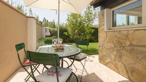An outdoor patio with a round table, four chairs, and a large umbrella.