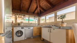 A kitchen with wooden cabinets, a washing machine, and a window with a view of the outside.