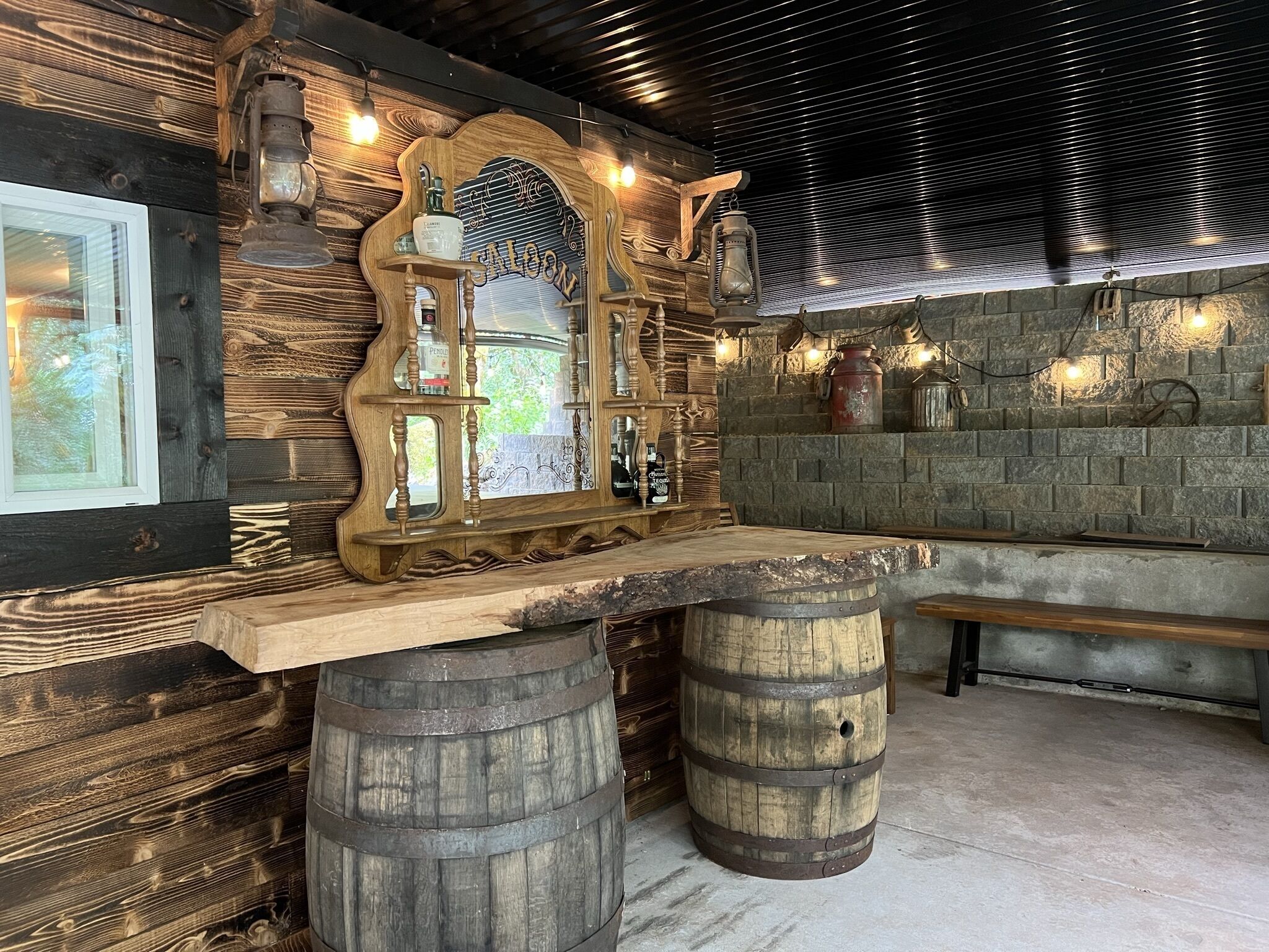 Um espaço de bar rústico com detalhes em madeira, um espelho grande e um painel de parede de pedra.