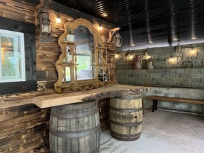 A rustic bar area with wooden accents, a large mirror, and a stone wall backdrop. - Unique Underground Speakeasy With Hot Tub (Damascus)