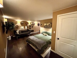 A bedroom with a bed, a couch, a dresser, and a door. - Unique Underground Speakeasy With Hot Tub (Damascus)