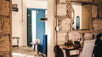 A rustic room with a stone wall, a wooden table, a chair, and a blue door.