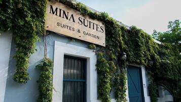 Un immeuble avec une enseigne indiquant « Mina Suites » et un jardin.