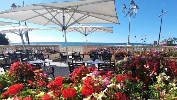Un espace extérieur aménagé avec des tables, des chaises, des parasols et une vue sur la mer.