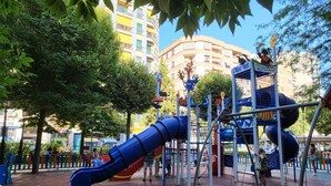 Un terrain de jeux avec des toboggans et des structures d’escalade, entouré d’arbres et de bâtiments.