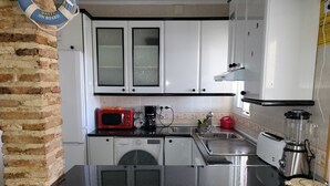 Une cuisine avec des meubles blancs, un four à micro-ondes rouge, une machine à café, un grille-pain et un mixeur.