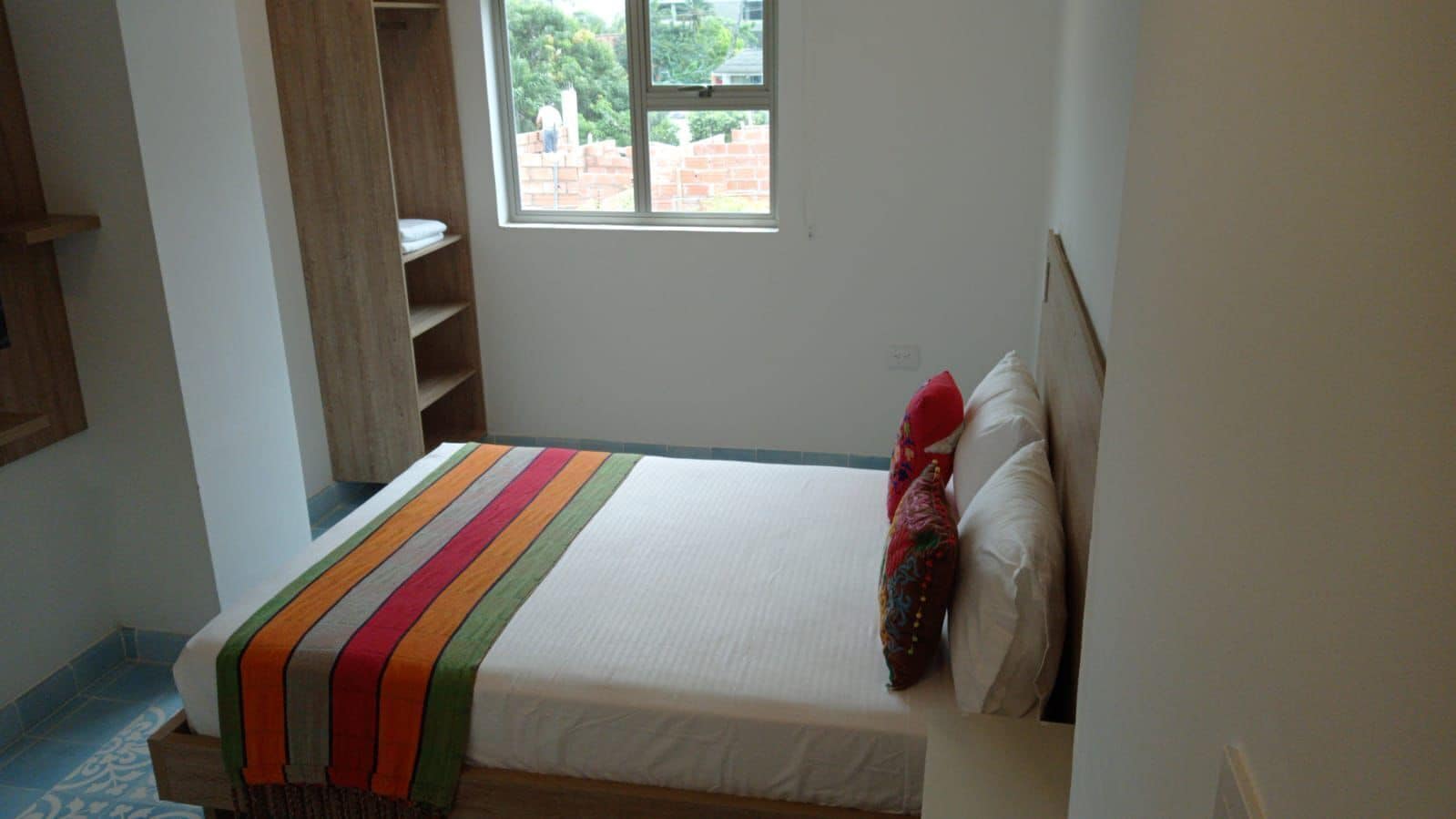 Une chambre à coucher avec un lit, une fenêtre et une étagère en bois.