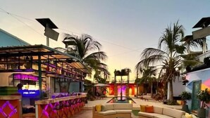 An outdoor lounge area with a fire pit, sofas, and a bar area with colorful lighting. - Hotel Coco Beach by Croma (Cartagena)