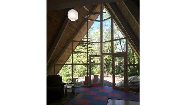 Una habitación con techo inclinado, ventanas amplias y suelo a cuadros.