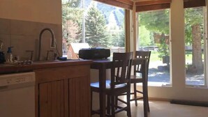Cocina con armarios de madera, lavavajillas y ventana con vistas a un área boscosa.