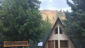Una cabaña pequeña de forma triangular con un porche, un letrero que dice 