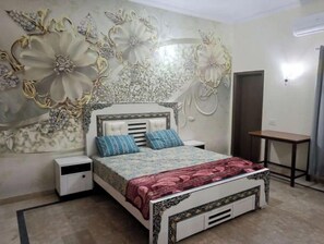 Ein Schlafzimmer mit Bett, Nachttischen, einem Schreibtisch und einer Wanddekoration.