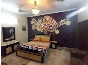 Relax in this serene bedroom with a large bed, nightstands, and a ceiling fan, surrounded by a beautiful floral mural and a framed picture.