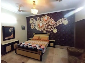Relax in this serene bedroom with a large bed, nightstands, and a ceiling fan, surrounded by a beautiful floral mural and a framed picture.